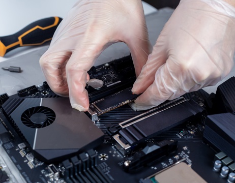 Technician is installing new fast high capacity SSD drive on the computer motherboard