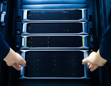 A technician manages multiple data storage units in a server rack, showcasing modern technology in computing environments for efficient data processing and management.